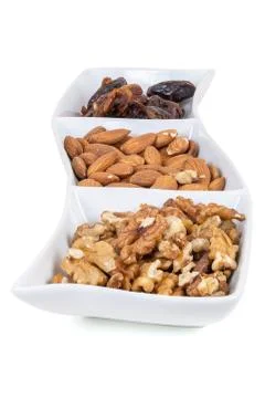 Walnuts almonds and dates in a white dish Stock Photos