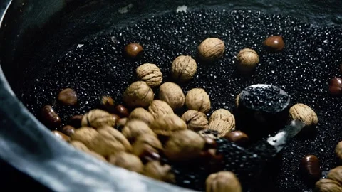 Walnuts and chestnuts roasting in hot sand at a street food market Stock Footage 325792580