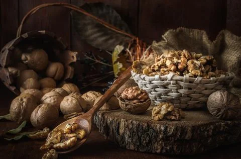 Walnuts and kernels in a basket on a dark wooden background Stock Photos