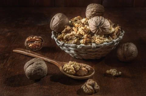 Walnuts and kernels in a basket on a dark wooden background Stock Photos