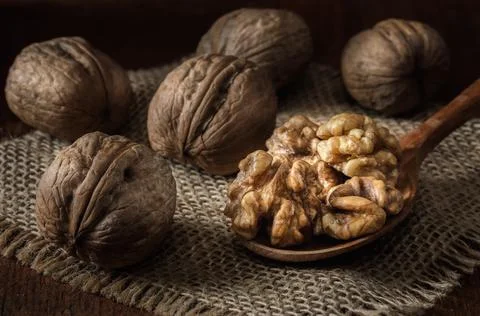 Walnuts and kernels in a basket on a dark wooden background Stock Photos