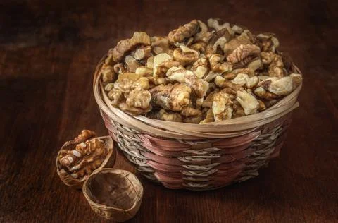 Walnuts and kernels in a basket on a dark wooden background Stock Photos