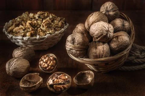 Walnuts and kernels in a basket on a dark wooden background Stock Photos