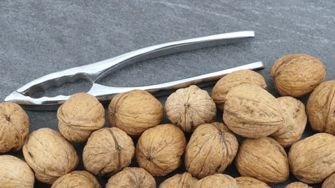 Walnuts and nutcracker on black stone background Stock Footage 85951455