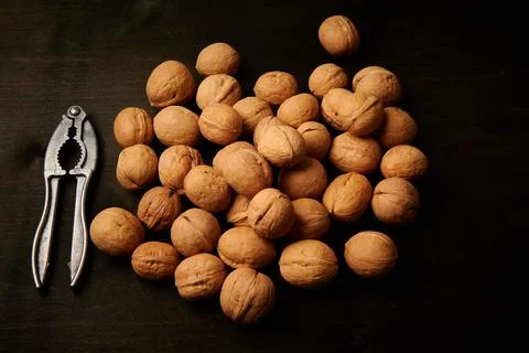 Walnuts and nutcracker on dark background top view Stock Photos