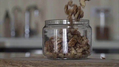 Walnuts and nuts are poured into a glass jar in the kitchen Stock Footage 72530911