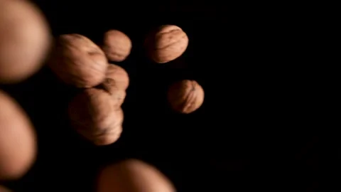 Walnuts are dumped from the left into black background in slow motion. Stock Footage 146884338