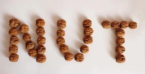 Walnuts arranged to spell "NUT" on a plain white surface Stock Photos