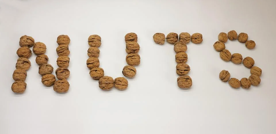 Walnuts arranged to spell "NUTS" on a plain white background Stock Photos