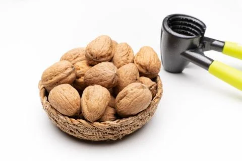 Walnuts in basket on white background next to nutcracker Foto stock