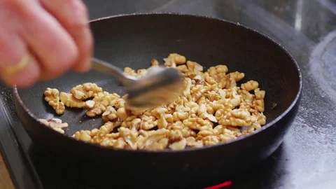 Walnuts being added and then roasted in a pan Stock Footage 84147670