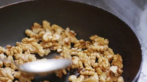 Walnuts being added and then roasted in a pan Stock Footage 84147683
