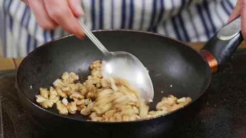 Walnuts being added and then roasted in a pan Stock Footage 84147692