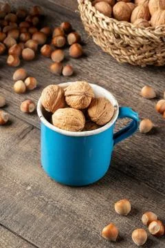 Walnuts in a blue pot with hazelnuts in the background Stock Photos