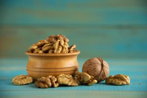 Walnuts on blue rustic table in wooden bowl Foto stock