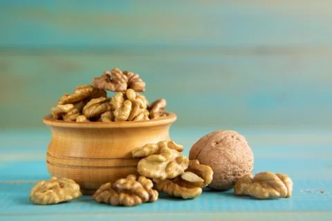 Walnuts on blue rustic table in wooden bowl Stock Photos