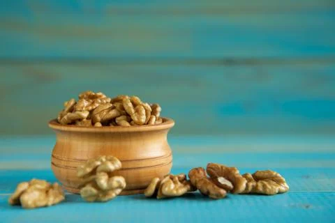 Walnuts on blue rustic table in wooden bowl Stock Photos