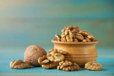 Walnuts on blue rustic table in wooden bowl Stock Photos