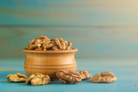 Walnuts on blue rustic table in wooden bowl Foto stock