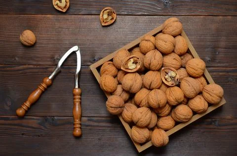 Walnuts in a box and a nutcracker on the table Stock Photos