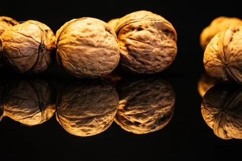 Walnuts on a dark reflective table. . Black background Stock Photos