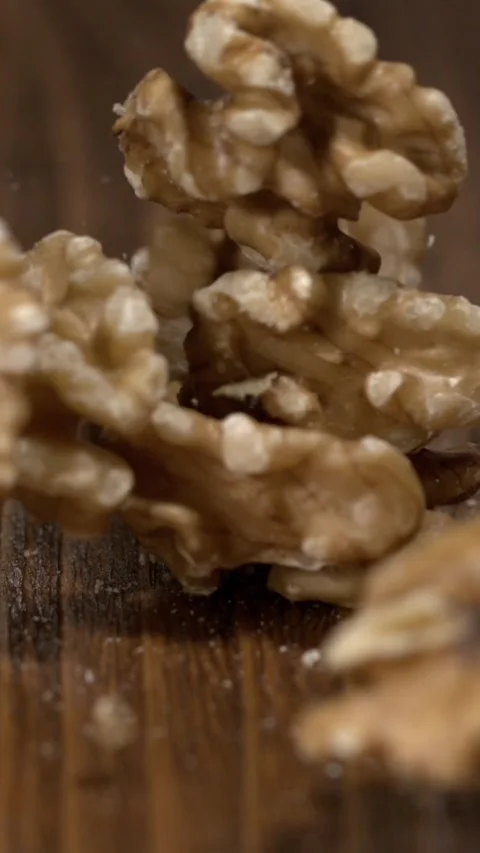 Walnuts fall on wooden surface in slow motion during a cooking demonstration Stock Footage 323147623