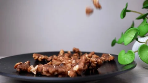 Walnuts falling onto a black plate with a plant in the background Stockbeeldmateriaal 320727290