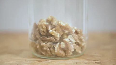 Walnuts falling into a glass jar. Brain-shapped nuts, good snack for healthy Stock Footage 329155501