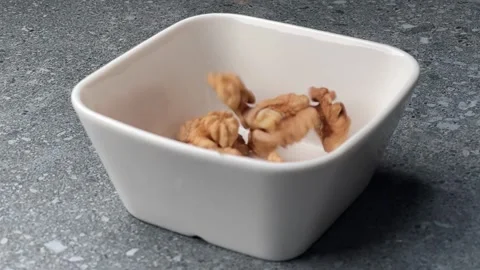 Walnuts falling into small white bowl close up macro slow motion Stock Footage 321158180
