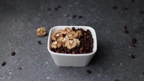 Walnuts falling into white bowl filled with roasted coffee beans Stock Footage 320848672