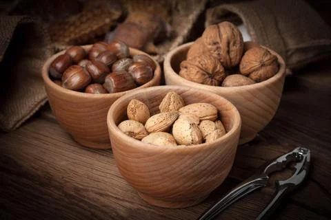 Walnuts, hazelnuts and almonds in-shell in wooden bow Stock Photos