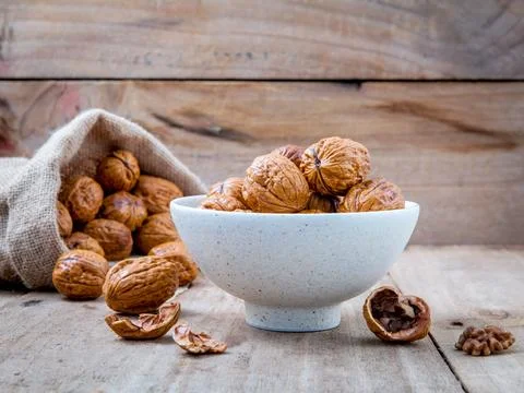 Walnuts kernels in hemp sack and whole walnuts on rustic old wooden backgroun Stock Photos