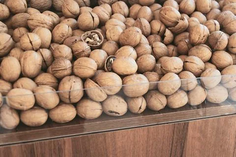 Walnuts in a nut shop window. A mountain of unpeeled walnuts in the market. W Stock Photos