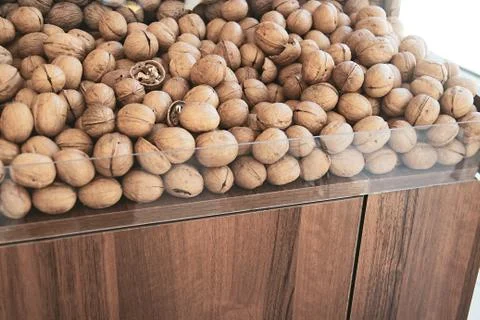 Walnuts in a nut shop window. A mountain of unpeeled walnuts in the market. W Stock Photos