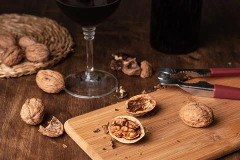 Walnuts with a nutcracker and next to a glass of wine and a bottle. Close-up. Stock Photos