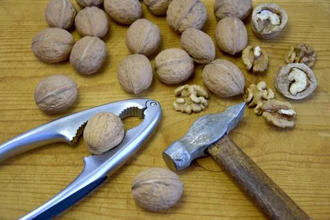 Walnuts, nutcracker and old hammer on wooden background. Close-up 写真素材