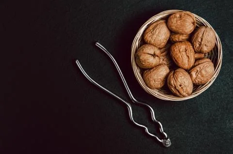 Walnuts with nutcracker on black background, top view. Photos