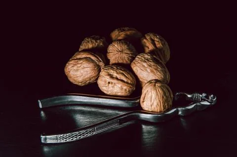 Walnuts with nutcracker over black background. Fotos Stock