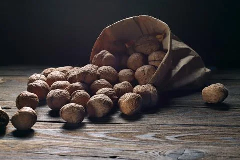 Walnuts on an old rustic table. Walnuts in a paper bag. Stock Photos