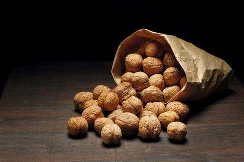 Walnuts on an old rustic table. Walnuts in a paper bag. Stock Photos