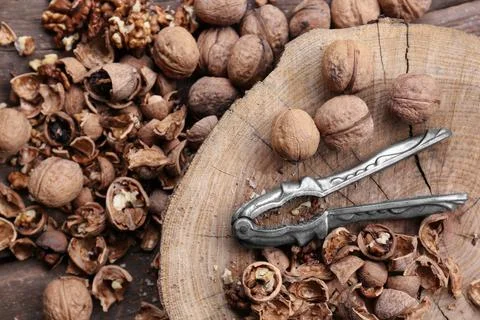 Walnuts, pieces of shells and nutcracker on wooden table, flat lay Foto stock