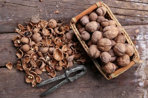 Walnuts, pieces of shells and nutcracker on wooden table, flat lay Foto stock