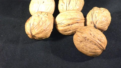 Walnuts in pile are rotating on wheel with shadow with black surface Video stock 111274269
