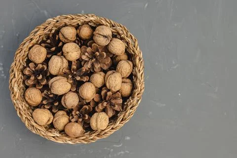 Walnuts in shell and pine cones in basket as Christmas table decoration Stock Photos