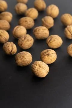 Walnuts in shell on black surface, side view. Healthy nuts and seeds background. Stock Photos