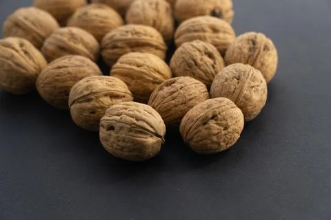 Walnuts in shell on black surface, side view. Healthy nuts and seeds background. Stock Photos