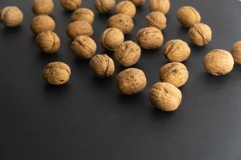 Walnuts in shell on black surface, side view. Healthy nuts and seeds background. Stock Photos