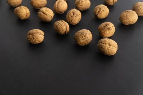 Walnuts in shell on black surface, side view. Healthy nuts and seeds background. Stock Photos