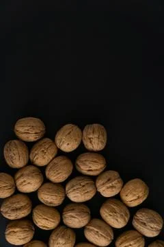 Walnuts in the shell on black surface, top view. Background of round walnuts Stock Photos