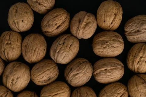 Walnuts in the shell on black surface, top view. Background of round walnuts Stock Photos